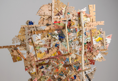 An abstract sculpture made up of countless thin pieces of wood, joined to each other by notches in the side. Most pieces are a plain pale wood, but some are painted in different vibrant colors.